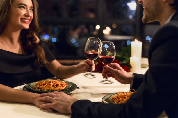 restaurant date woman man glasses wine pasta smiling touching eating candles dinner