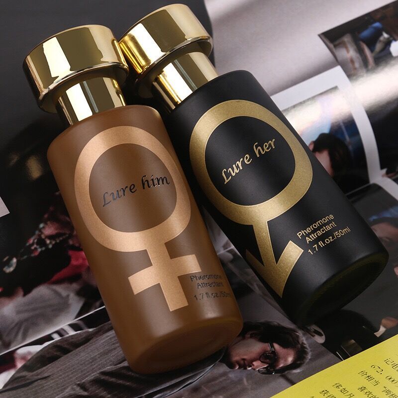 Two pheromone perfume bottles in black and  gold with matching caps and labels, sitting on a magazine surface. The black bottle features a cylindrical shape. Pheromone perfumes can enhance attraction and influence mood, making them a popular choice for romantic occasions. Names are lure him and lure her. Designed to seduce women 